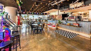 Un restaurant doté d’un bar, de tables, de chaises et de jeux d’arcade.