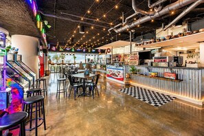 Ein Restaurant mit Barbereich, Tischen, Stühlen und Spielautomaten.