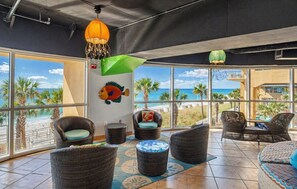 A spacious room with wicker furniture, large windows offering a beach view, and a decorative fish wall art piece. - Splash Into Paradise | Gulf-Front 20th Floor Retreat at Splash Resort (Panama City Beach)