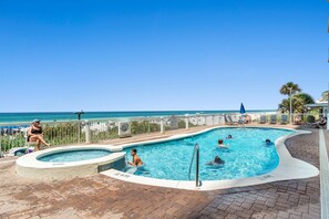 Un área de piscina con vistas al océano, un jacuzzi pequeño y sillas de descanso.
