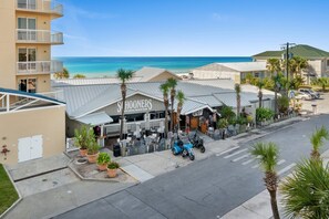 Un hotel frente a la playa con un letrero que dice "Schooners 1st Local Beach Club", un estacionamiento y vista al océano.