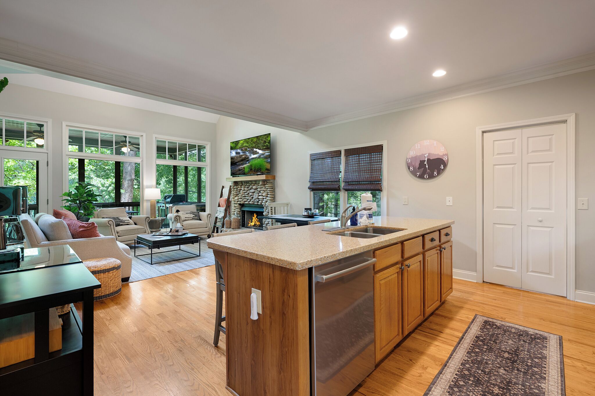 A spacious living area with a kitchen island, wooden cabinets, and a large window.