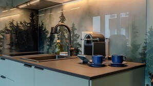 Une cuisine moderne dotée d’un évier encastré, d’une machine à café et d’une fresque murale décorative.