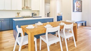 Eine moderne Küche mit weißen Schränken, einem Holzespeisetisch und weißen Stühlen.