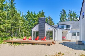 A modern house with a deck, red chairs, and a large window. - Beach House w/ Patio & Game Room (CoastalC) (Long Beach)