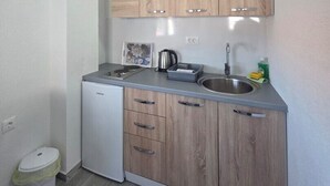 Una cucina compatta con mobili in legno, un lavello incassato e un piccolo frigorifero.
