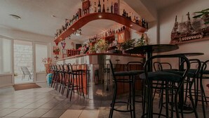 Zona de bar con una estructura de madera curvada, varios taburetes y una variedad de botellas en estanterías.
