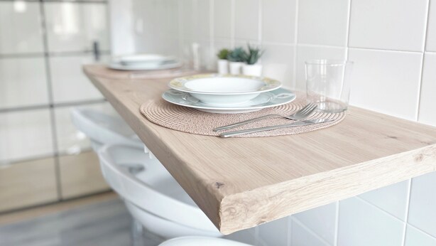 A kitchen counter with white plates, a glass, and cutlery on a woven placemat. - NA&DIA HOME by wehomes (Santander)