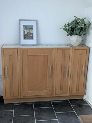 A wooden cabinet with a framed picture and a potted plant on top. - Luxury Retreat Contractors| Business| Families (Tow Law)