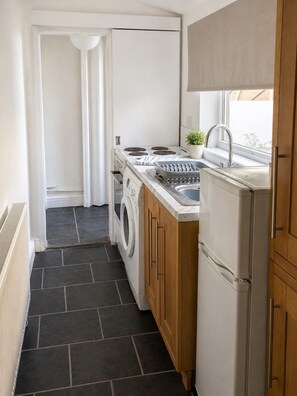 A compact kitchen with a washing machine, a stove, and a sink. - Luxury Retreat Contractors| Business| Families (Tow Law)