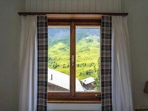 Ein Fenster mit Blick auf eine grüne Landschaft und ein Gebäude.