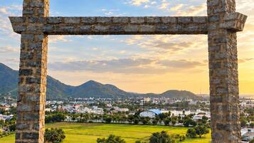 Eine Steinstruktur einer Pergola mit Blick auf eine Stadt und Berge im Hintergrund.