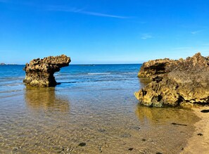 A beach with clear shallow waters and rocky formations. - Hon Do Eco Retreat (Ninh Chu)