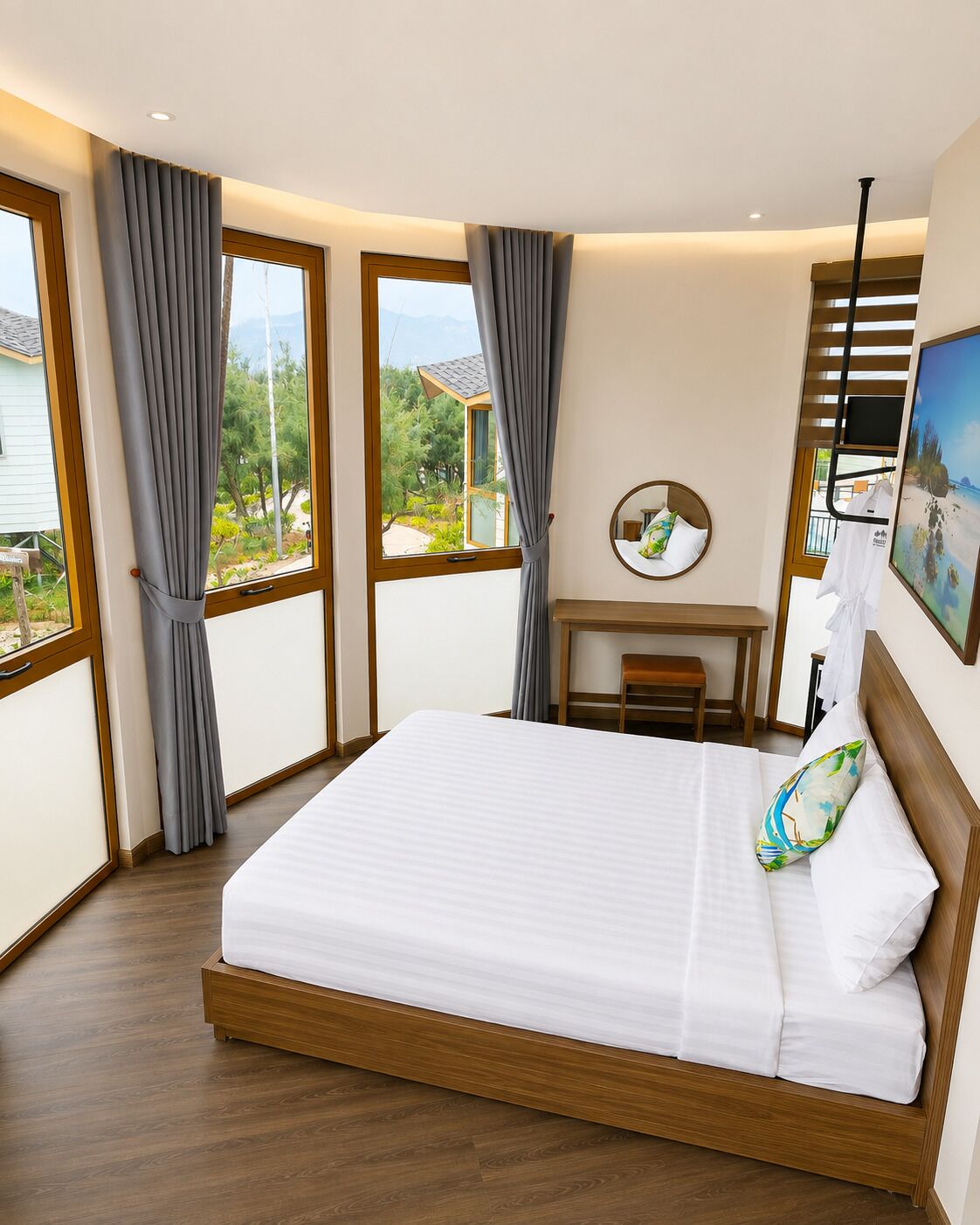Quarto com uma cama grande, uma escrivaninha e uma cadeira. Há cortinas nas janelas e um quadro na parede.