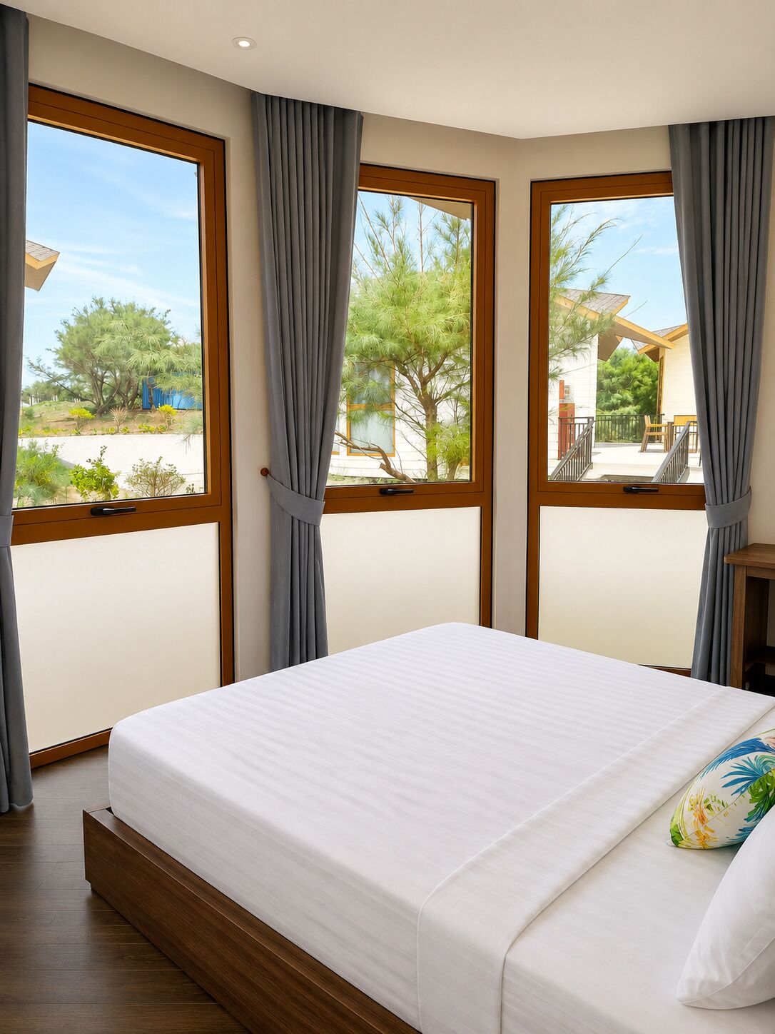 A bedroom with a large bed, two windows with curtains, and a view of the outdoors.