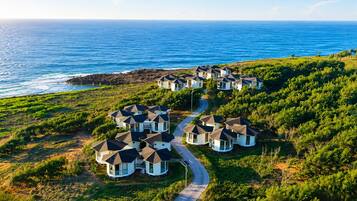 Zona residencial a la costa, amb cases disposades en semicercle al llarg d'un camí corbat, amb vistes a l'oceà.