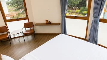 Een hotelkamer met een groot bed, een kleine tafel met stoelen, een airconditioning en uitzicht op het omliggende landschap.