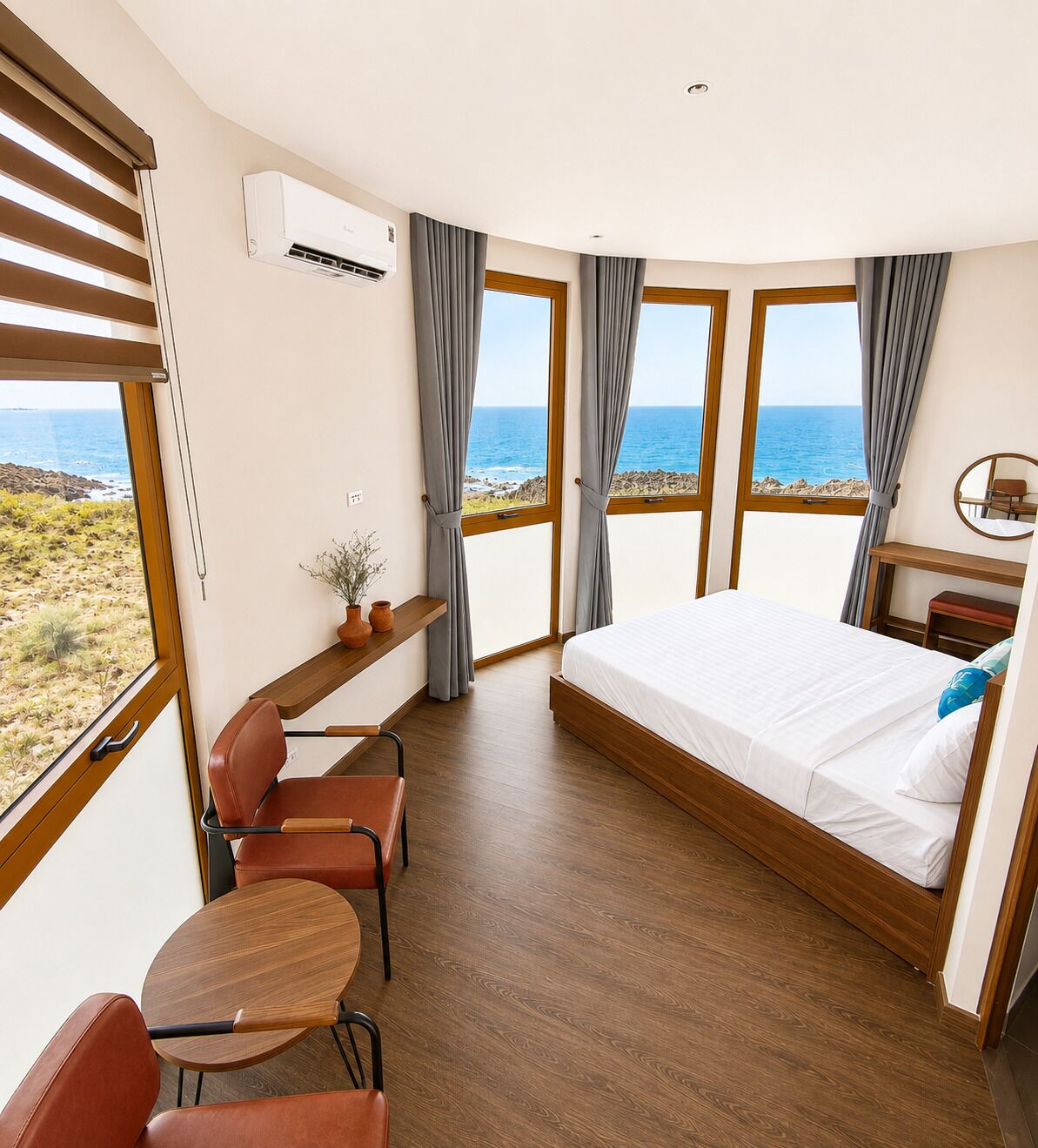 A bedroom with a large bed, a desk, and a chair, with a view of the sea.