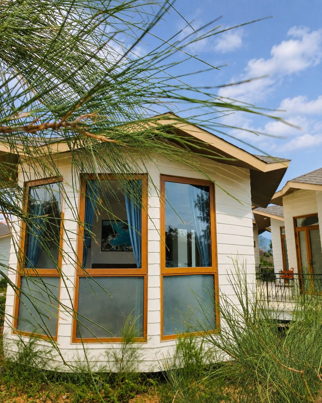 A house with large windows, a sloped roof, and a visible outdoor area.
