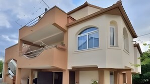 Uma casa de dois andares com varanda, garagem e uma bicicleta estacionada na frente.