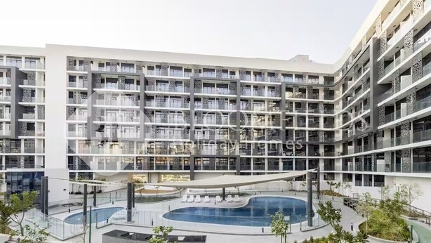En flereetagers boligbygning med altaner, en central gårdhave med swimmingpool og grøn bevoksning omkring.