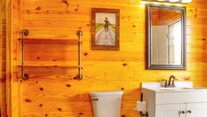 Et træinteriør med toilet, vask og et billede i ramme på væggen.