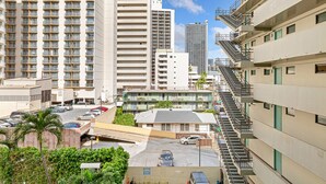 A multi-story parking garage with several cars parked, surrounded by high-rise buildings and a clear sky. - Chic Studio w/Kitchenette, Lanai, AC, WiFi–Waikīkī Grand #501 (Honolulu)