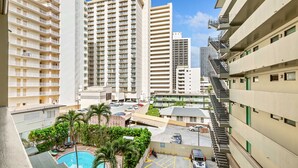 A high-rise hotel with multiple balconies, a swimming pool, and a parking area. - Chic Studio w/Kitchenette, Lanai, AC, WiFi–Waikīkī Grand #501 (Honolulu)