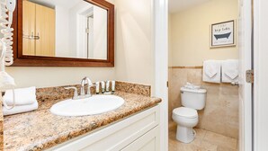 A bathroom with a granite countertop, a white sink, a mirror, a toilet, and a shower area. - Chic Studio w/Kitchenette, Lanai, AC, WiFi–Waikīkī Grand #501 (Honolulu)