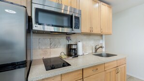 A kitchen with a stainless steel refrigerator, a microwave, a coffee maker, and a sink. - High-Style Studio w/Kitchenette, WiFi, Flat Screen+AC–Waikiki Grand 503 (Honolulu)
