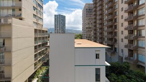 Un edificio residencial de varios pisos con balcones, un edificio central blanco y un rascacielos a lo lejos.