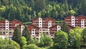 Eine Reihe mehrstöckiger Gebäude mit Balkonen, umgeben von dichtem Wald.