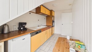 Cocina compacta con lavamanos, cafetera y un refrigerador pequeño.