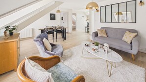 Una sala moderna con techo alto, comedor y sofá gris.
