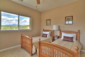A bedroom with two wooden beds, a nightstand, a lamp, and a window with a mountain view. - New Listing! Golf Course & Mtn Views | A/C | Spacious Townhome (Pagosa Springs)