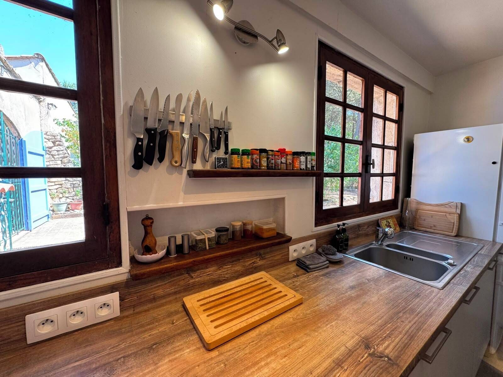 A kitchen with a wooden countertop, a sink, a window, and a wall-mounted knife rack.