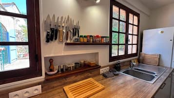 A kitchen with a wooden countertop, a sink, a window, and a wall-mounted knife rack.