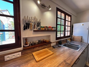 Eine Küche mit Holzausziehtisch, Spüle, Fenster und einem an der Wand befestigten Messerblock.