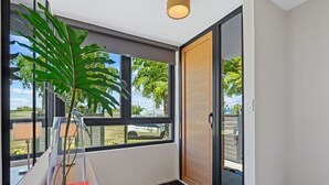 A modern interior with a large window, a potted plant, and a wooden door. - Cozy 2BR in Miramar | Kitchen, Laundry & TVs (San Juan)
