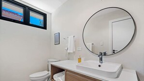 Uma casa de banho moderna com sanita, lavatório e espelho.