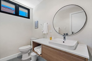 A modern bathroom with a toilet, sink, and mirror. - Stylish Studio in Miramar | Work Desk + Smart TV (San Juan)