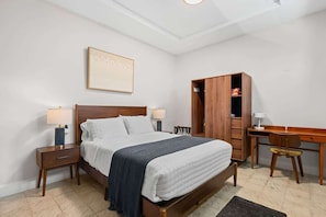 A bedroom with a bed, bedside tables, a desk, and a wardrobe. - Stylish Studio in Miramar | Work Desk + Smart TV (San Juan)