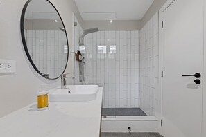 Une salle de bain moderne avec un lavabo blanc, un miroir et un espace douche.