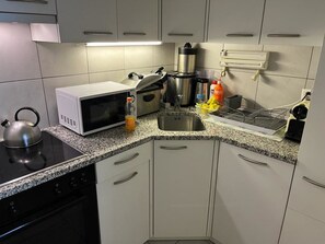 A modern kitchen with a microwave, kettle, coffee maker, and a dish rack. - Fortuna 403 # 4-bed apartment, Dusche, WC 4-Bettwohnung, Dusche, WC by Interhome (Leukerbad)