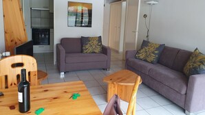 Ein Wohnzimmer mit einer Couch, einem Couchtisch und einem Esstisch, auf dem sich eine Flasche und Schlüssel befinden.