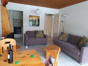 A living room with a sofa, a coffee table, and a dining table with a bottle and keys. - Fortuna 403 # 4-bed apartment, Dusche, WC 4-Bettwohnung, Dusche, WC by Interhome (Leukerbad)