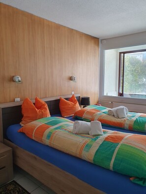 A hotel room with two beds, wooden headboards, and a large window. - Fortuna 403 # 4-bed apartment, Dusche, WC 4-Bettwohnung, Dusche, WC by Interhome (Leukerbad)