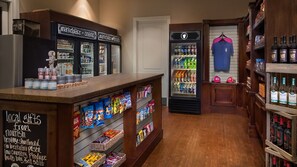 L’intérieur d’un magasin, avec des étagères remplies d’en-cas et un réfrigérateur où sont exposées des boissons en bouteille.