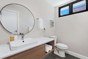 Ein Badezimmer mit Waschbecken, runder Spiegel und Toilette.