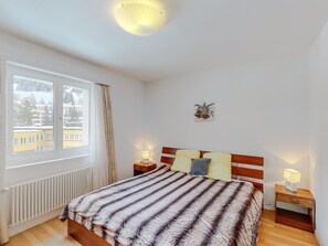 Ein Schlafzimmer mit einem Bett, zwei Nachttischen, einem Fenster und einem Wandbild.